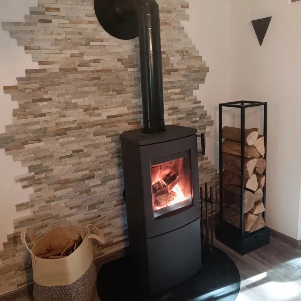 Poêle à bois installé dans un séjour par E-FIRE, avec son range-bûches